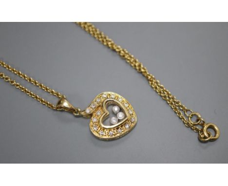 A modern Chopard style 18k and 'floating' diamond set heart shaped pendant, on a 750 chain, pendant 18mm, gross 8.3 grams.