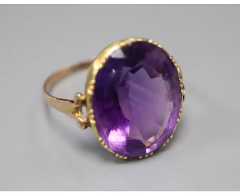 A 19th century gold and amethyst dress ring (tests as 9ct), with collet setting and carved scrolled shoulders, size J/K, gros