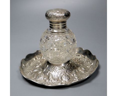 A late Victorian repousse silver mounted glass inkwell, on a repousse silver stand, London, 1891, height 14.4cm.