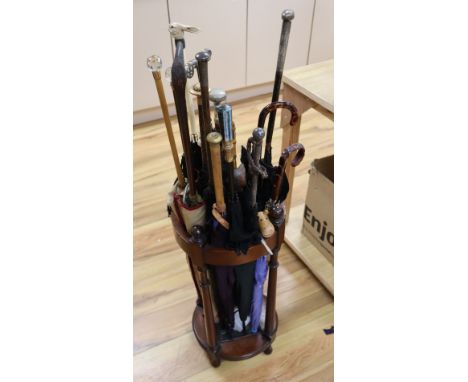 A collection of novelty and decorative parasols, contained within a cylindrical mahogany stick stand