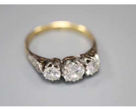 A mid 20th century '18ct and plat' three stone diamond ring, with diamond set shoulders, size K/L, gross 2.4 grams.CONDITION: