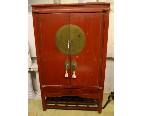 A Chinese two-door brass-mounted red-lacquered cupboard fitted three short drawers over an open shelf, width 110cm, depth 60c