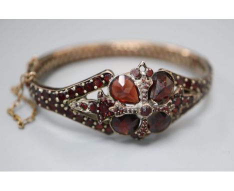 A Victorian gilt white metal and garnet set hinged bangle.