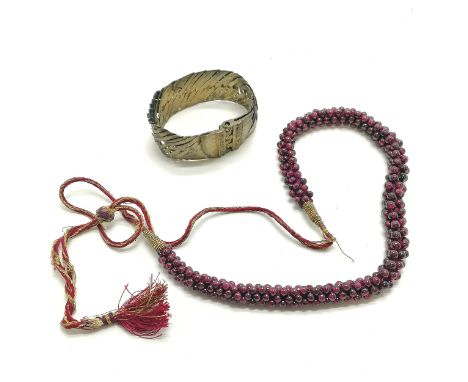 Strand of garnet beads on a silk cord (worn) t/w ethnic bangle 