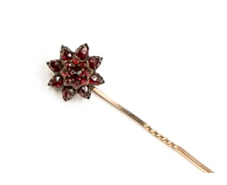 A Victorian garnet and rose metal flowerhead stick pin, the centre round mixed cut garnet with round mixed cut garnet surroun