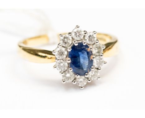 A Sapphire and diamond cluster ring, set with an oval corn flower blue sapphire approx 7x5mm surrounded by ten diamonds equat
