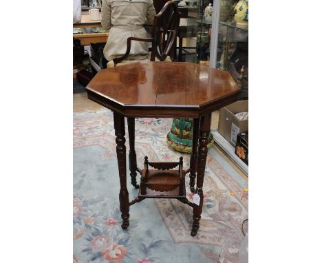 A hexagonal mahogany occasional table, having galleried lower shelf, four carved legs on wheels 