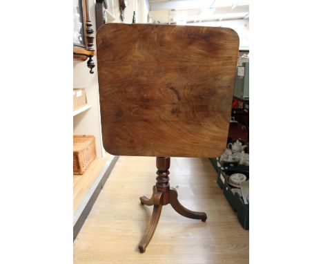 An early 19th Century mahogany tilt-top tripod table, the square top raised on a turned column and three sabre legs