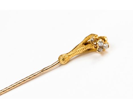 A Victorian novelty yellow metal stick pin, in the form of a scaled four clawed foot clasping a diamond set shamrock, three o