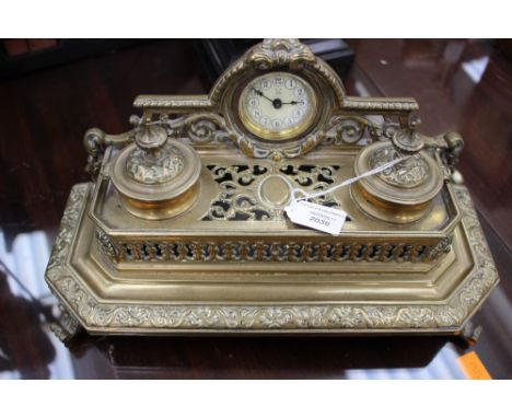 A brass inkwell with mounted clock in the centre, pierced decoration 