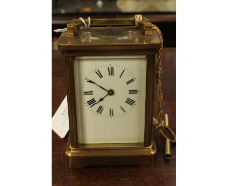 A brass carriage clock, having enamelled dial, with Roman numerals, minor chips to bevelled glass key 