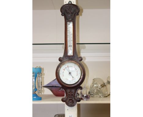 A carved mahogany wheel barometer, with thermometer, the barometer having enamelled dial  