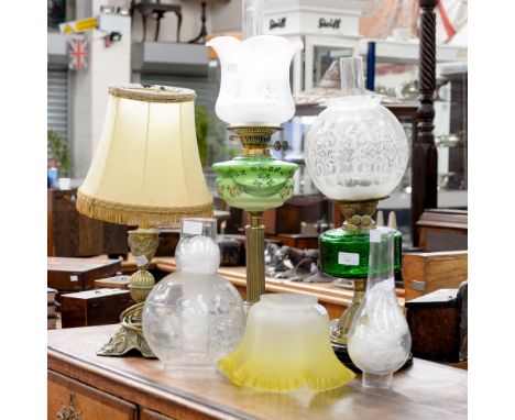 A late Victorian oil lamp with a double wick, complete with a funnel and glass shade, green glass reservoir; together with a 