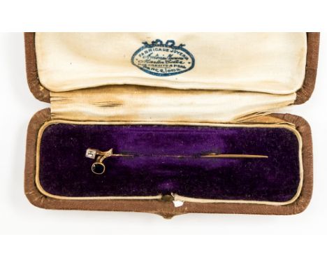 An Edwardian diamond and sapphire yellow metal stick pin in the form of a sprig, bezel set with millegrain edging, the cushio