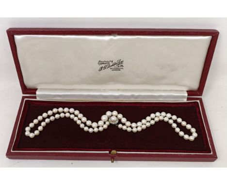 A cultured pearl necklace, with a diamond clasp, in a vintage jewellery box