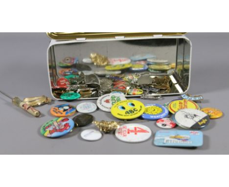 A tin and contents of various lapel badges and keyrings to include enamel examples.