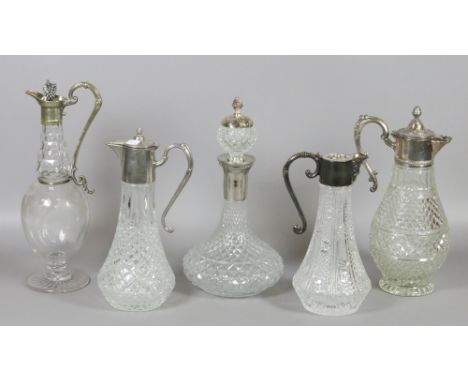 Four white metal topped claret jugs and a similar decanter.