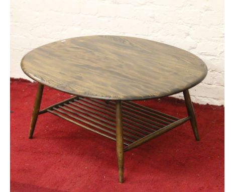 An Ercol circular coffee table with magazine rack raised on circular supports.