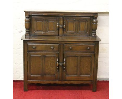 An Ercol style court cupboard raised on square supports.