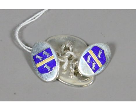 A pair of silver cufflinks enamelled with a crest.