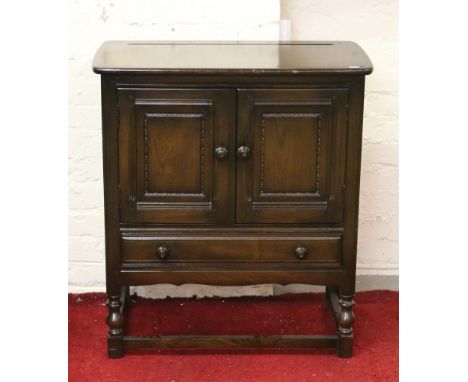 An Ercol two door cabinet raised on turned supports.