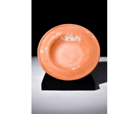 Ca. 100-300 AD.A redware plate fashioned with a shallow and rounded countenance showcases a broad flange encircling the basin
