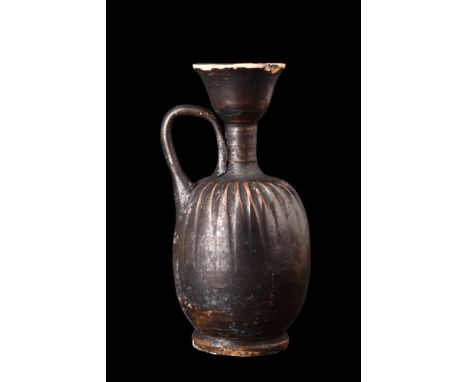 Ca. 5th century AD.A black-glaze lekythos displays a roundish body that rests upon a ring base, providing stability and balan