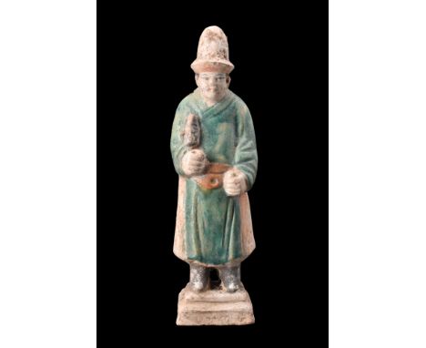 Ca. 1368-1644 AD or later .A glazed terracotta mingqi depicting a standing attendant on a tiered, integral base. He is portra