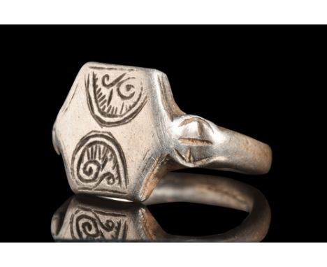 Ca. 1000 AD.A silver finger ring of a solid band, elegantly hewn, envelops the finger with an understated grace. The centrepi