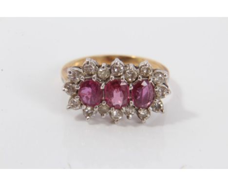 Gold (18ct) ruby and diamond cluster ring with three oval mixed cut rubies surrounded by a border of sixteen brilliant cut di