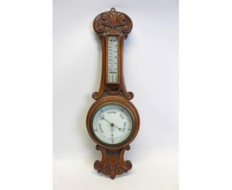 Early 20th century aneroid barometer with 5 inch circular dial and separate thermometer in a carved oak case, 60cm overall le