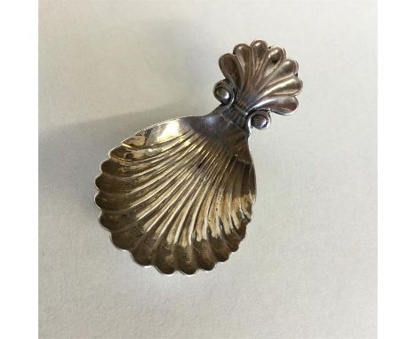 A Georgian silver fluted caddy spoon with shell thumb piece. Birmingham. By JL. Approx. 10 grams. Est. £30 - £50.