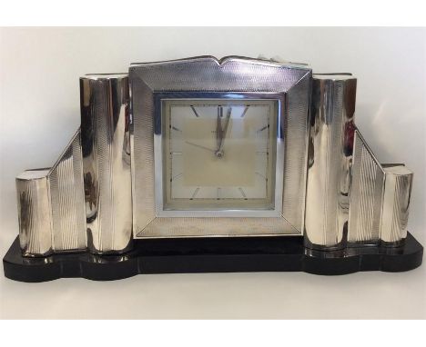 A large stylish silver clock of engine turned design on wooden base. Approx. 34 cms x 17 cms. Est. £200 - £300.