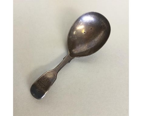 A large Georgian silver fiddle pattern caddy spoon with crested thumb piece. London. By GA. Approx. 15 grams. Est. £30 - £50.