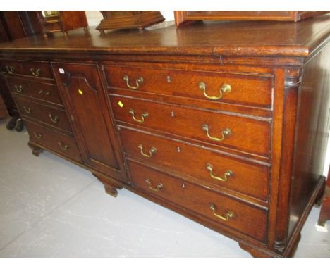 Large 19th Century oak dresser having central fielded panelled shaped door flanked by eight long graduated crossbanded drawer