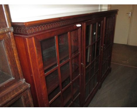 Edwardian mahogany three door dwarf bookcase having blind fretwork frieze above three bar glazed doors on bracket feet