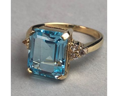 BLUE AND WHITE GEM SET RING, the step cut blue gem 10mm long, flanked by round white gems on either shoulder, in nine carat g