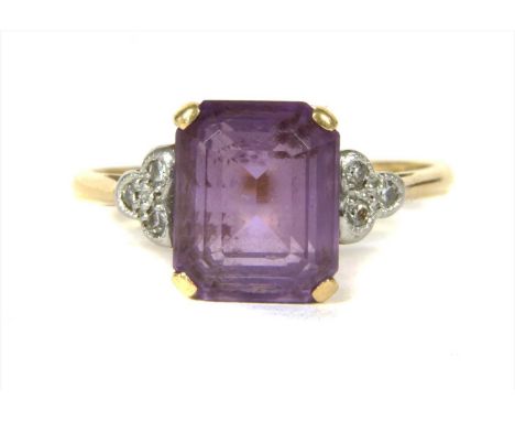 A gold amethyst and diamond ring, with an emerald cut amethyst, claw set to a trefoil of eight cut diamonds, milligrain set a