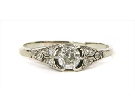 A white gold diamond ring, with an old European cut diamond, claw set to pierced tapered shoulders, grain set with eight cut 
