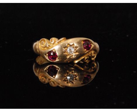 An early 20th Century 18ct hallmarked ruby and diamond three stone ring central diamond flanked by rubies, gypsy set on a sli