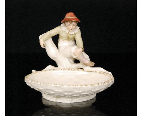 A Royal Worcester comport modelled by James Hadley as a young boy dressed in a green shot enamel shirt and a red bonnet sat u