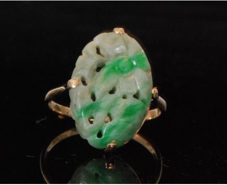 An early 20th Century 9ct oval single stone jade ring, pierced in a floral design and claw set to plain shoulders, length of 