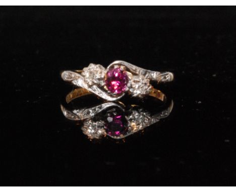 An 18ct hallmarked ruby and diamond three stone ring, central ruby flanked by diamonds to either side set on a slight twist, 