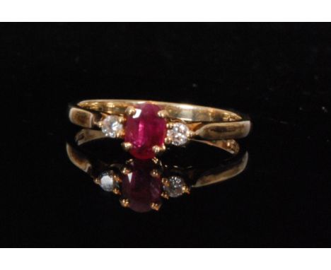 A 9ct ruby and diamond three stone ring, central ruby flanked by brilliant cut diamonds to knife edged shoulders, ring size Q