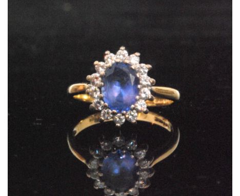 A modern 18ct hallmarked tanzanite and diamond cluster ring, central oval tanzanite within fourteen stone brilliant cut diamo