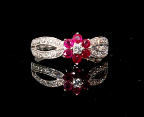 A modern 18ct hallmarked white gold diamond and diamond ring, central diamond within six stone ruby surround to split pave di