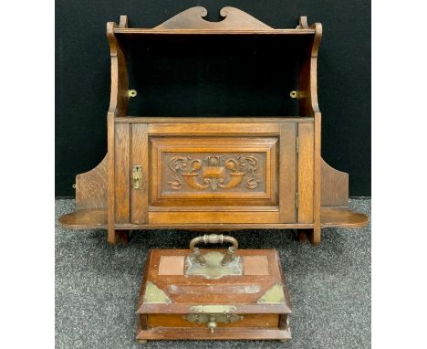 An early 20th century Arts and Crafts style oak wall cupboard, single shelf to top, above a small cupboard door with carved p