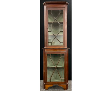 An Edwardian Sheraton revival, satinwood cross-banded, mahogany corner cabinet, the astral-glazed doors enclosing two tiers o