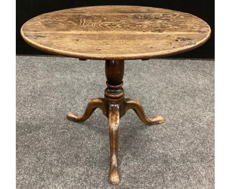 A George III oak table, circular plank top, turned column, tripod feet, 56cm high, 68cm diameter, (later alterations). 