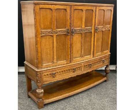 A mid 20th century oak three-door bow-front buffet side cabinet, carved panelled doors, above a pair of drawers, shelf to bas